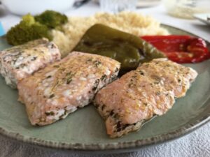 Salmón con verduras al horno servido con salsa de mostaza y limón, acompañado de pimientos asados y brócoli al vapor.