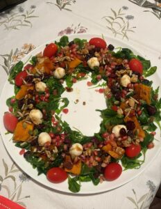 Ensalada en forma de corona con brotes verdes, calabaza asada, granada, tomates cherry y bolitas de mozzarella.