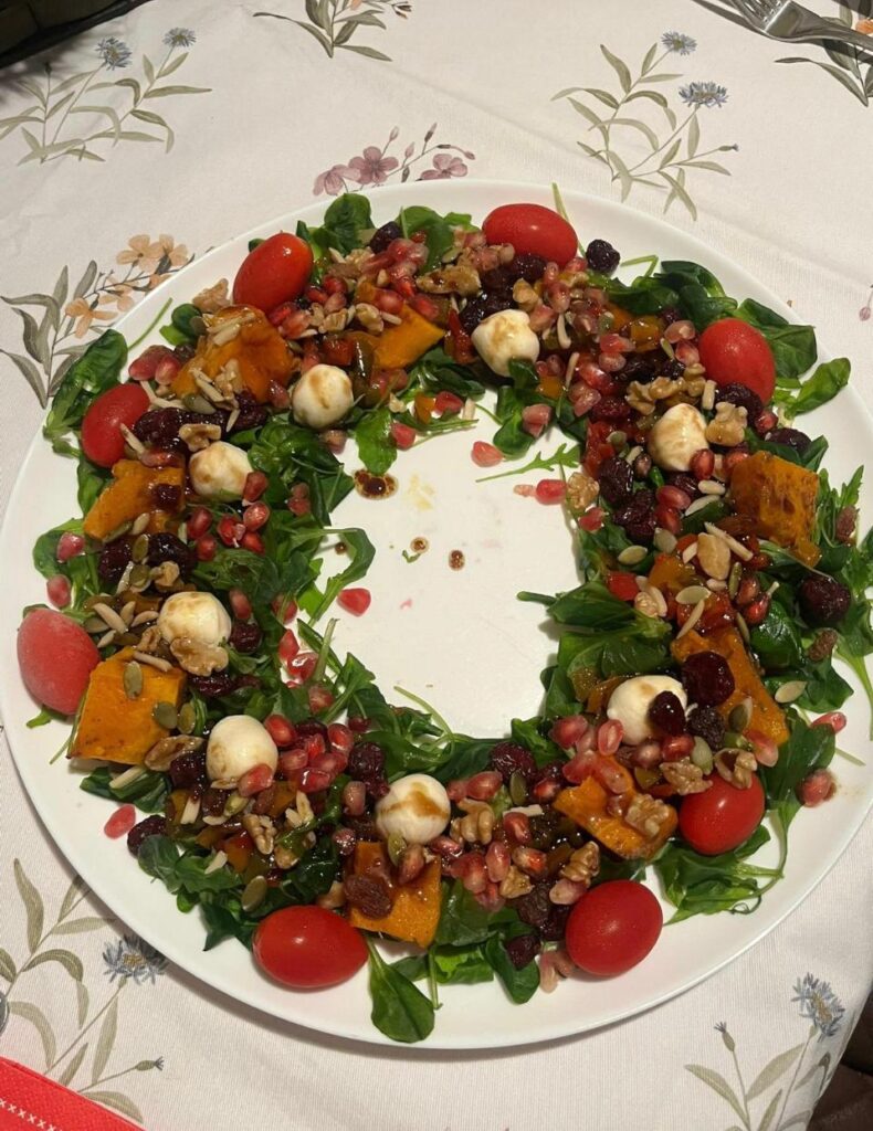 Ensalada en forma de corona con brotes verdes, calabaza asada, granada, tomates cherry y bolitas de mozzarella.